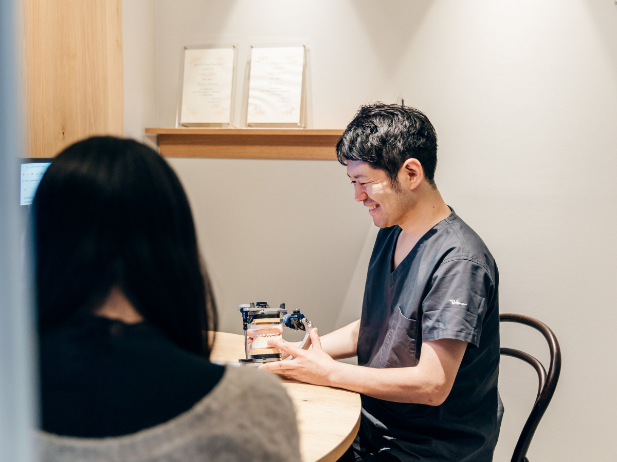 歯科医師が患者に歯の模型で説明している様子